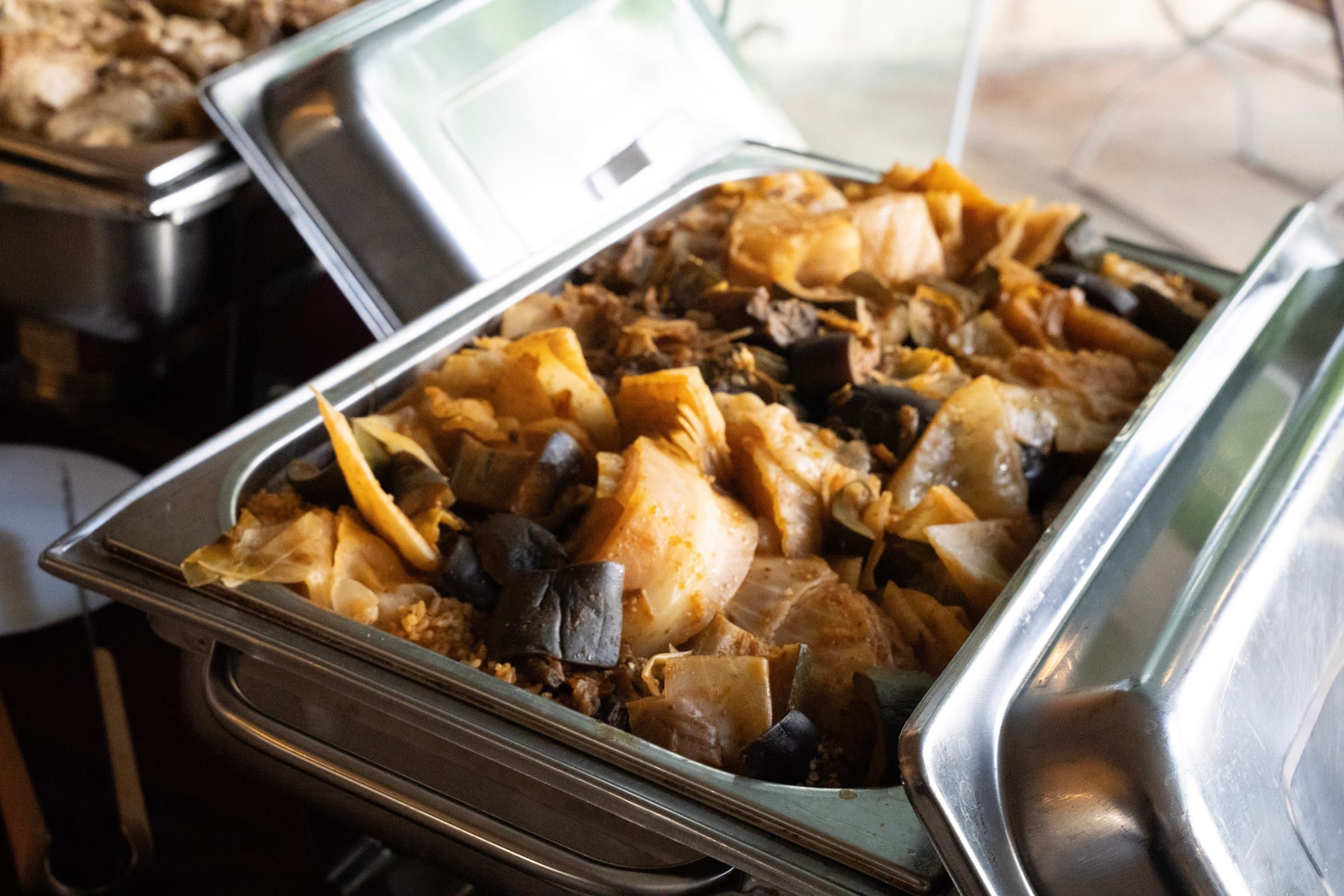 Chou braisé et aubergines dans un chauffe-plat ouvert, lors d’un buffet.